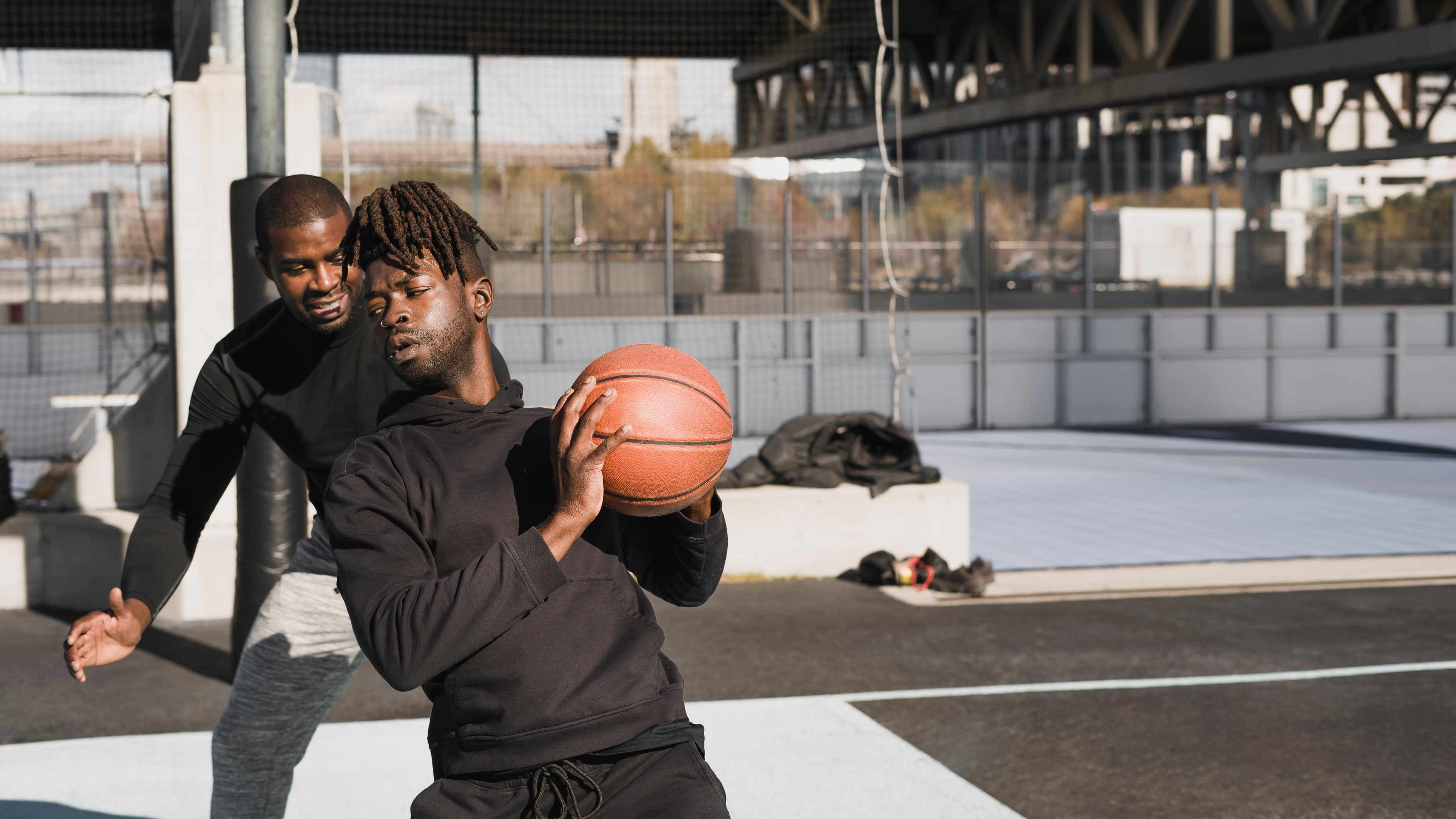 Two men playing basketball on an outdoor urban court